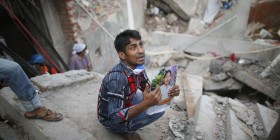 996473-relative-holds-picture-of-a-garment-worker-in-front-of-the-rubble-of-the-collapsed-rana-plaza-buildi